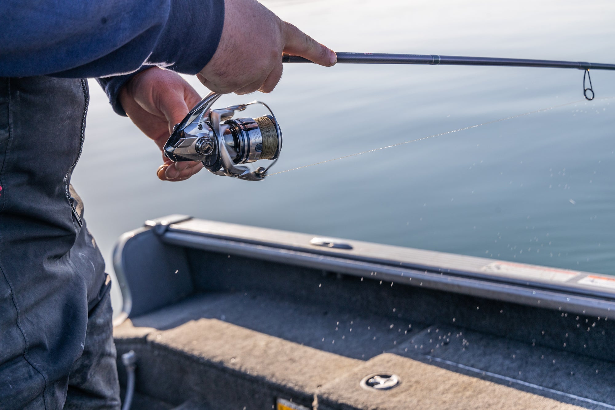 Closeup of someone's hands reeling in their fishing pole. 