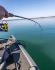 A pair of hands holding onto their fishing pole with the line in the water. 
