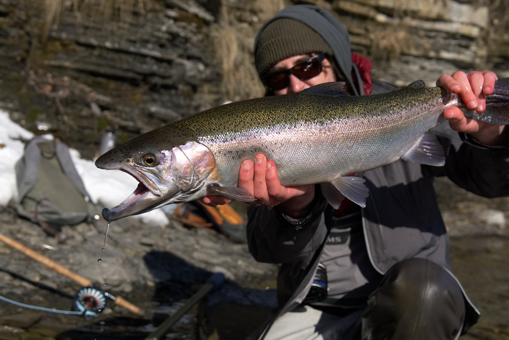 An angler kneeling down and holding up a fish. 